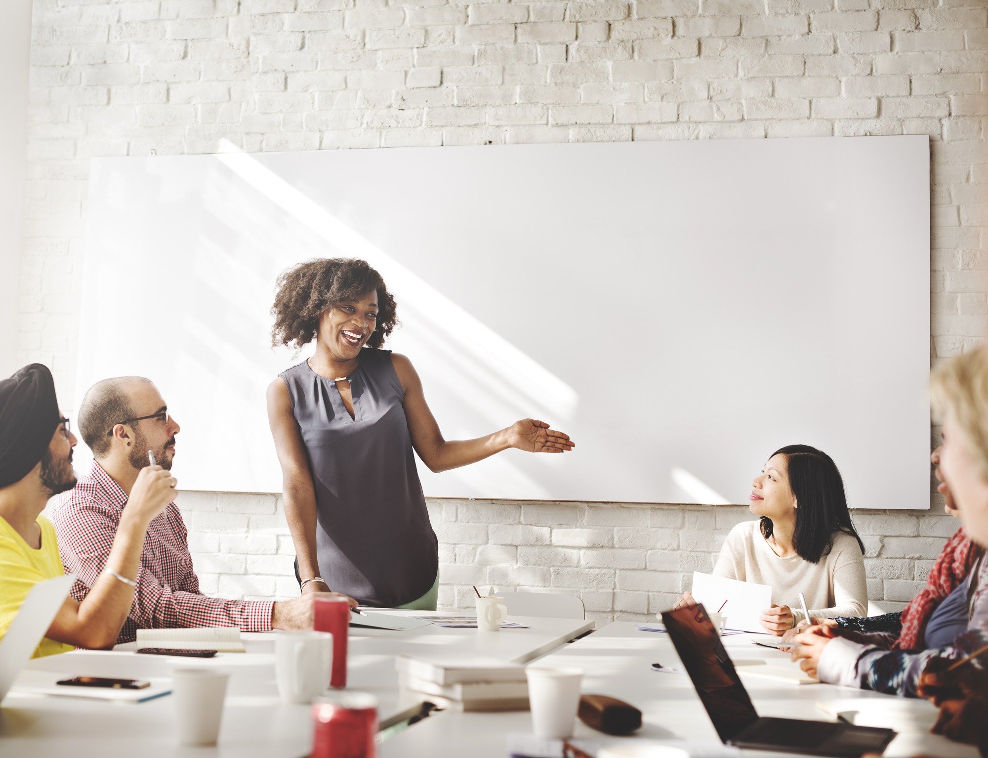 A woman leads a team meeting in a bright, modern office. Colleagues attentively engage, fostering collaboration and creativity.
